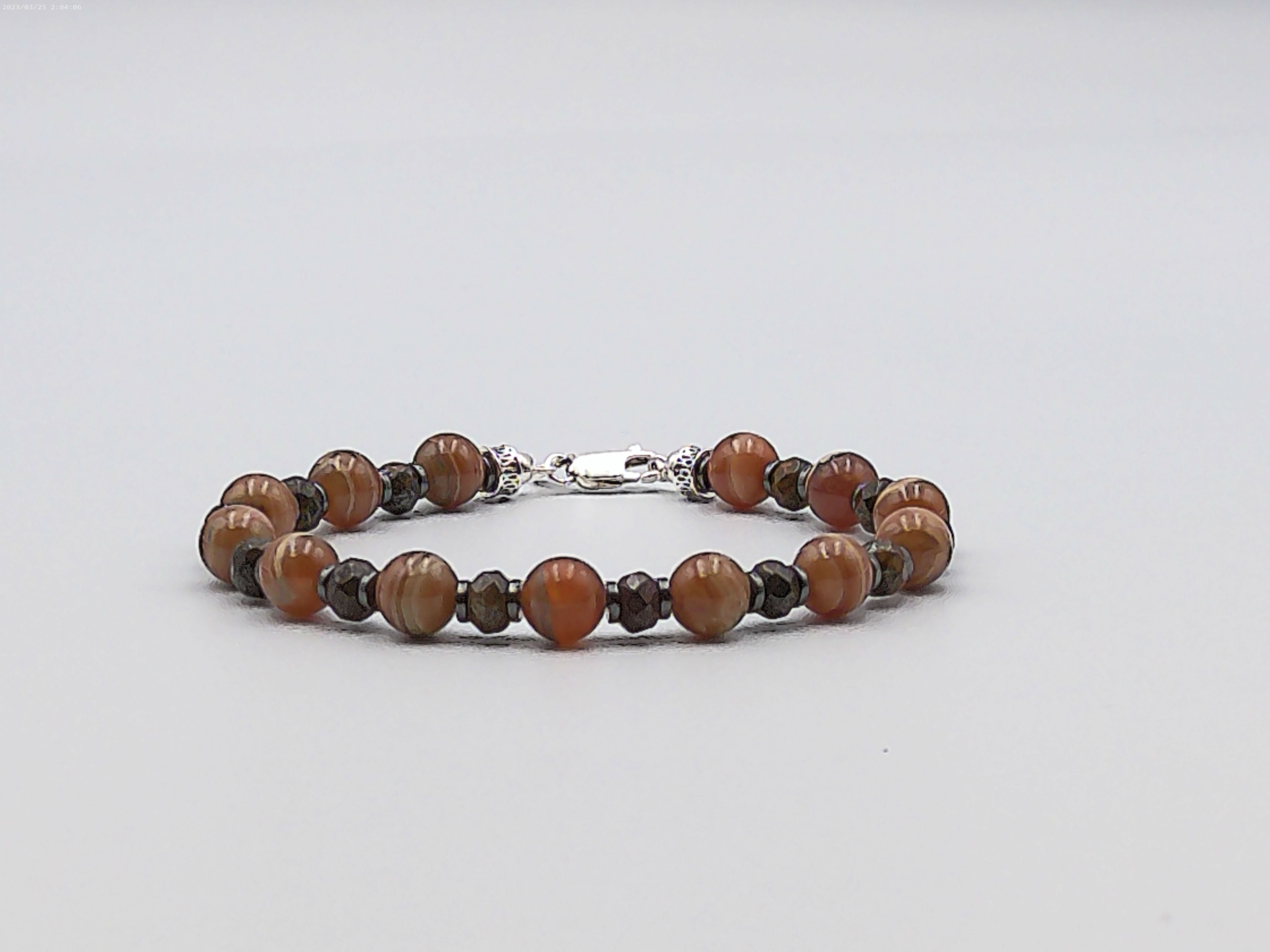 Il bracciale è realizzato con perle di Rodocrosite, gemme di Bronzite ed ematite. Rifinito con accenti in Argento sterling 925 e pratica chiusura a moschettone in Argento sterling 925.